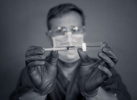 COVID-19 Coronavirus Vaccine. Doctor scientist with syringe analyzing virus Sars-CoV-2 in research for vaccine to be ready for clinical trial. Male researcher testing potential vaccine at the lab.の写真素材