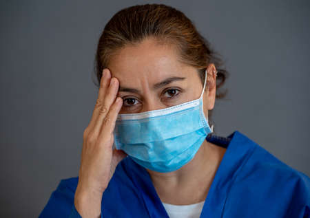 COVID-19. Exhausted Doctor looking worried as the coronavirus infected cases and death tolls rises. Emotional stressed of health workers needing support, Personal Protective gear and medical supplies.の写真素材