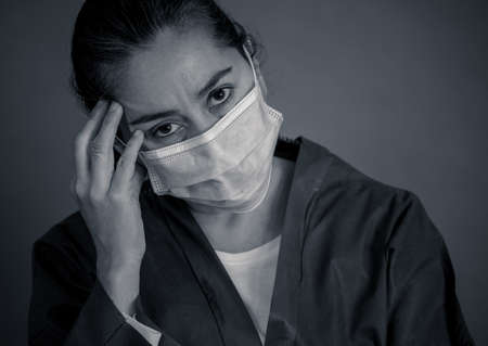 COVID-19. Exhausted Doctor looking worried as the coronavirus infected cases and death tolls rises. Emotional stressed of health workers needing support, Personal Protective gear and medical supplies.の写真素材
