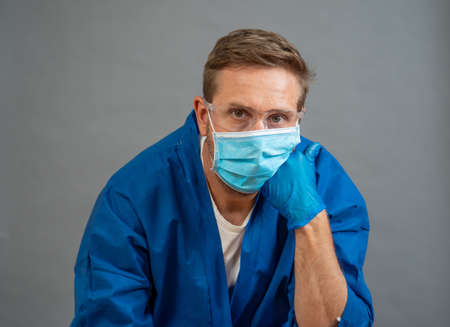 COVID-19. Exhausted Doctor looking worried as the coronavirus infected cases and death tolls rises. Emotional stressed of health workers needing support, Personal Protective gear and medical supplies.の写真素材
