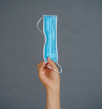 Coronavirus disease outbreak. Hand holding face surgical mask. Stop the virus spread, Protect yourself and others from COVID-19 and Lack of PPE personal protective equipment supplies concept.の写真素材