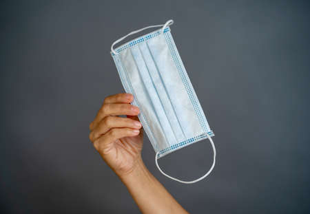 Coronavirus disease outbreak. Hand holding face surgical mask. Stop the virus spread, Protect yourself and others from COVID-19 and Lack of PPE personal protective equipment supplies concept.の写真素材