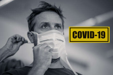 COVID-19 Save lives campaign. Strong image of hands helping young man putting face mask. In Stay Healthy, Stop the coronavirus spread, together we can and Worldwide Health alert concept.の写真素材