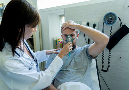 Female doctor with sick man patient with Oxygen Mask in hospital emergency room. In Smoking and respiratory diseases and anti tobacco advertising campaign.の写真素材