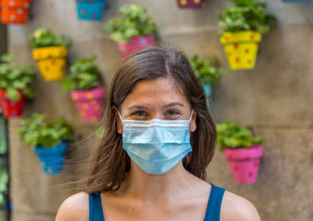 Young woman wearing surgical mask on face in public spaces. Coronavirus spreading protection mask protective against influenza viruses and diseases. Positive image of New Normal life after COVID-19の写真素材