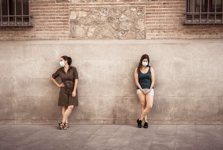 Two woman wearing protective face masks standing 2 m from each other keeping social distancing avoiding the spread of coronavirus. Conceptual image of COVID-19 disease protection and New Normal.の写真素材