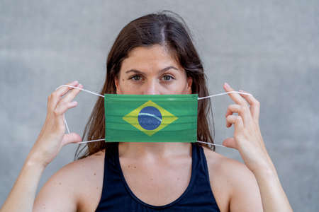 Young woman wearing Brazil flag face mask against infectious diseases 2019 Novel Coronavirus. Conceptual portrait with copy space of Protection against Covid-19 coronavirus outbreak in Brazil.の写真素材