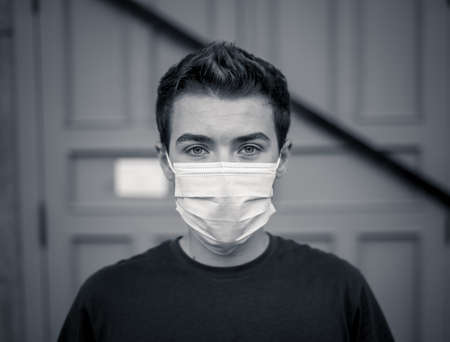 Young man wearing medical protective surgical face mask against infectious Coronavirus disease. Conceptual portrait of New Normal and Protection against Covid-19 outbreak.の写真素材