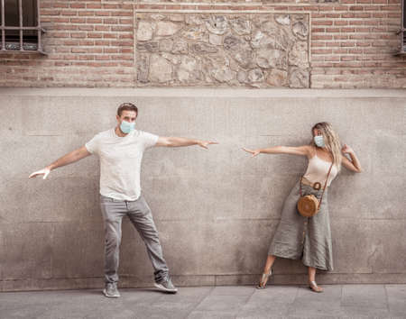 Man and woman wearing face mask standing 6 feet from each other keeping social distancing avoiding...