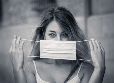 Young woman wearing protective face mask outdoors in city street. Positive image of New Normal life after COVID-19 and health protocols to avoid infections and the virus spread in public spaces.の写真素材