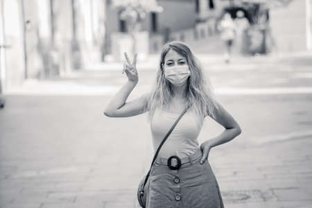 Young woman wearing protective face mask outdoors in city street. Positive image of New Normal life after COVID-19 and health protocols to avoid infections and the virus spread in public spaces.の写真素材