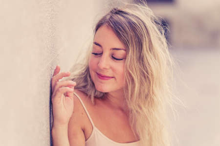Outdoors close up portrait of young attractive woman with beautiful blonde hair and sensual smile. Female model posing with natural beauty and light. Real People, beauty care, fashion and lifestyle.の写真素材