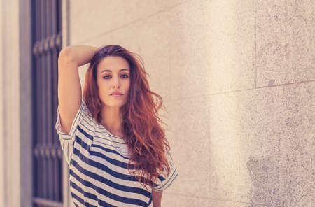Outdoors close up portrait of young attractive woman with curly red hair and sensual smile. Female...