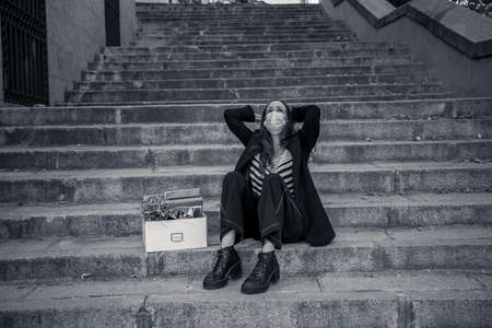 COVID-19 lay off and unemployment. Depressed business woman with face mask outside office with...