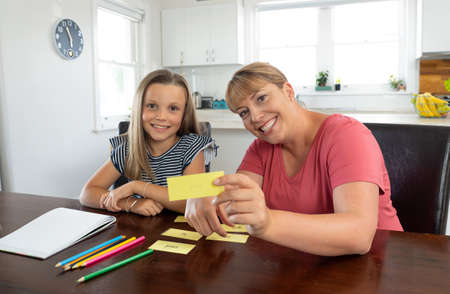 Mother helping child daughter studying at home in self-isolation or quarantine. Education, Home schooling, Remote learning and School closures due to Coronavirus second wave concept.の写真素材