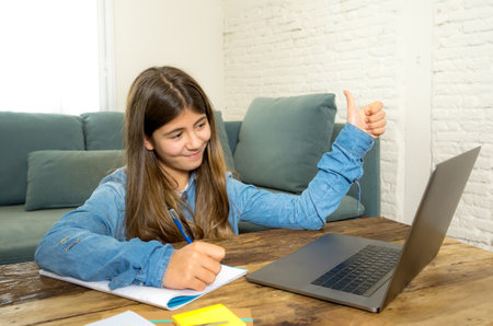Happy Teen girl on laptop studying online in virtual remote class on the internet at home as high...