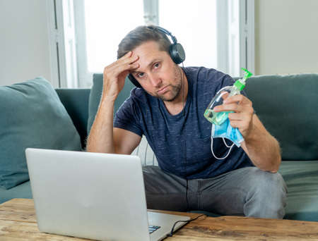 Stressed business man on laptop working from home looking worried, tired and overwhelmed.
