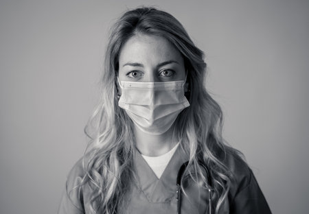 Portrait of female doctor or nurse wearing scrub and protective medical face mask. Emotional stress of overworked healthcare professionals and medical care team during covid-10 period.の写真素材