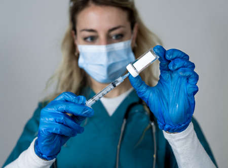 Doctor, nurse, scientist hand in blue gloves holding flu, measles, coronavirus, covid-19 vaccine...