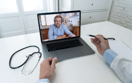 Screen laptop with caucasian man video calling physician for medical advice or treatment. Medical student studying medicine in online video conference with doctor. Health care and e-learning.の写真素材