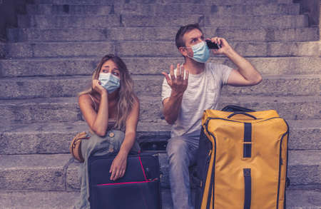 Sad tourist couple with mask and luggage ready for summer vacations trip worried about virus test...