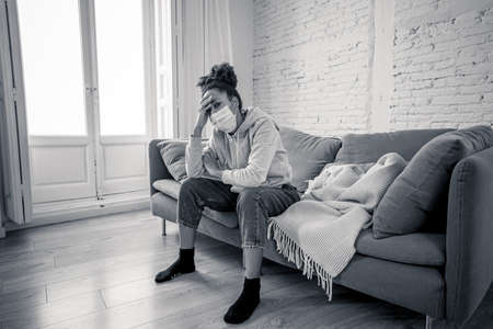 Unhappy lonely young african american woman suffering from anxiety, stress and depression feeling alone and distressed at home. Mental health and social isolation among young people concept.の写真素材