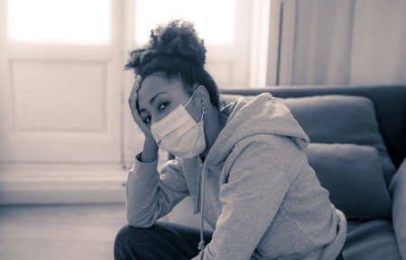 Unhappy lonely young african american woman suffering from anxiety, stress and depression feeling alone and distressed at home. Mental health and social isolation among young people concept.の写真素材