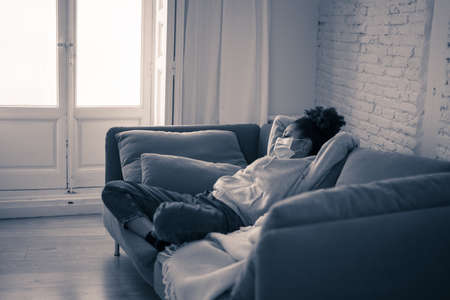 Unhappy lonely young african american woman suffering from anxiety, stress and depression feeling alone and distressed at home. Mental health and social isolation among young people concept.の写真素材