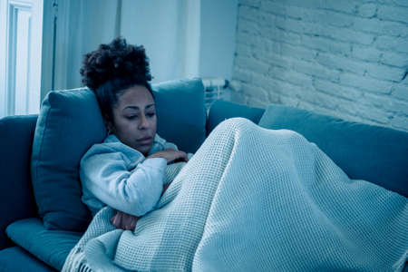 Depressed african woman with sad expression, headache and depression feeling desperate at home. Afro...