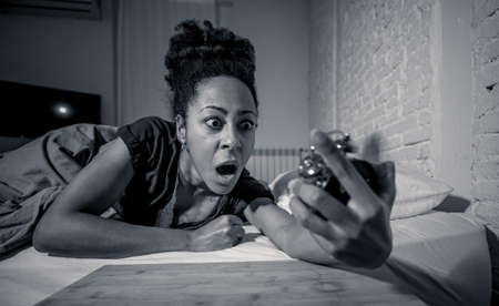Young beautiful afro american woman at home lying in bed late at night trying to sleep suffering insomnia sleeping disorder or scared on nightmares looking stressed and worried Mental health concept.の写真素材