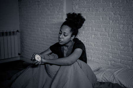 Young beautiful afro american woman at home lying in bed late at night trying to sleep suffering insomnia sleeping disorder or scared on nightmares looking stressed and worried Mental health concept.の写真素材