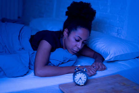 Young beautiful afro american woman at home lying in bed late at night trying to sleep suffering insomnia sleeping disorder or scared on nightmares looking stressed and worried Mental health concept.の写真素材