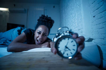 Young beautiful afro american woman at home lying in bed late at night trying to sleep suffering insomnia sleeping disorder or scared on nightmares looking stressed and worried Mental health concept.の写真素材