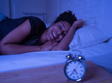 Young beautiful afro american woman at home lying in bed late at night trying to sleep suffering insomnia sleeping disorder or scared on nightmares looking stressed and worried Mental health concept.の写真素材