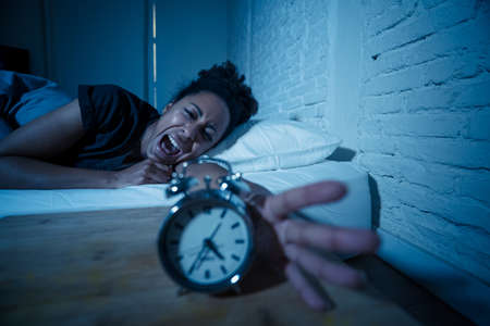 Young beautiful afro american woman at home lying in bed late at night trying to sleep suffering...