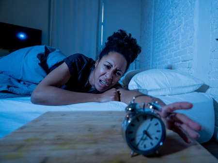 Young beautiful afro american woman at home lying in bed late at night trying to sleep suffering insomnia sleeping disorder or scared on nightmares looking stressed and worried Mental health concept.の写真素材