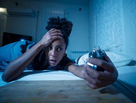 Young beautiful afro american woman at home lying in bed late at night trying to sleep suffering insomnia sleeping disorder or scared on nightmares looking stressed and worried Mental health concept.の写真素材
