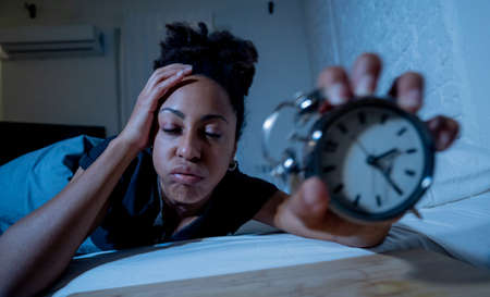 Young beautiful afro american woman at home lying in bed late at night trying to sleep suffering insomnia sleeping disorder or scared on nightmares looking stressed and worried Mental health concept.の写真素材