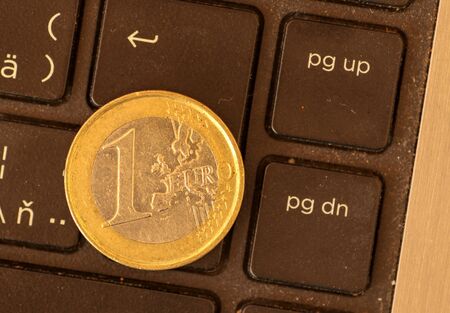 Euro coins lie on a laptop keyboard. Close up, space for text. Concept of working on the Internet or online payment for purchase. Laptop keyboard and coin 1 Euro.の写真素材