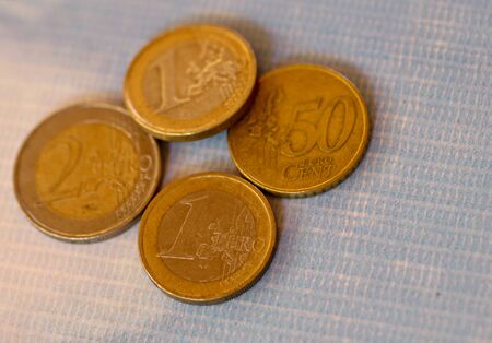 Euro coins stacked on each other in different positions. A closeup of coins a blue table under the...
