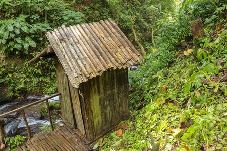 Changing room built of bamboo trunks by a river in a tropical rain forest. Small house at Spray Waterfall on Bali Island high in the mountains. Valley with river in tropical jungle.の写真素材