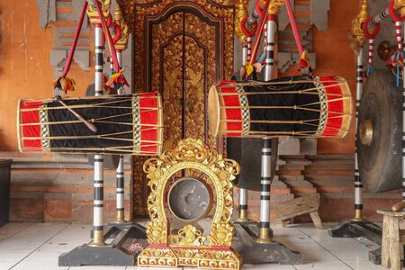 Musical instruments in a Hindu temple on Bali island, Indonesia. Drums and gongs suspended on load-bearing wooden ornate constructions. Musical instruments used in ceremonies.の写真素材