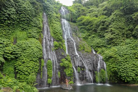 Secret jungle waterfall cascade in tropical rainforest with rock and turquoise blue pond. Banyumala twin waterfall in mountain slope in Bali, Wanagiri, Indonesia. Nature water slide waterfall.の写真素材