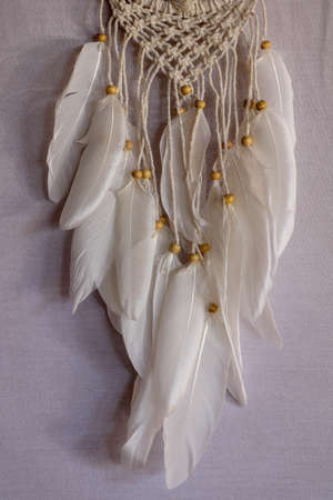 Handmade pink dream catcher with white doily on background of rocks and lake. Tribal elements,...