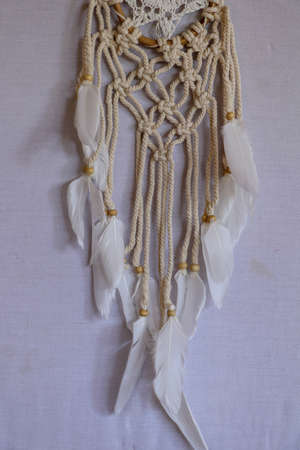 Handmade pink dream catcher with white doily on background of rocks and lake. Tribal elements,...