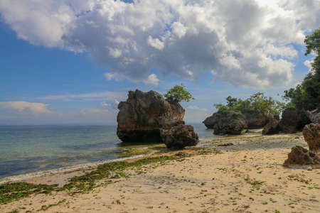 Impossible Beach in Bali Indonesia, nature vacation background. Giant boulders and rock formations jutting out over the Indian Ocean.の写真素材