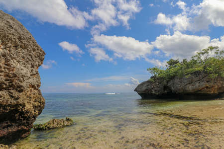 Padang Padang Beach in Bali Indonesia - nature vacation background. Giant boulders and rock formations jutting out over the Indian Ocean.の写真素材