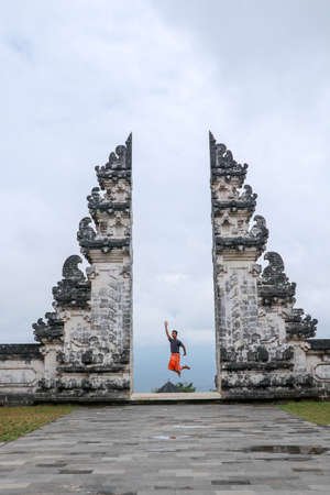 Bali, Indonesia. Young taveler man jumping with energy and happiness in the gate of heaven. Lempuyang temple.