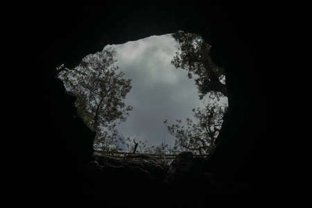 View from inside a cave looking out.Fallen cave ceiling. A hole in the ceiling of the cave.の写真素材