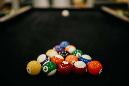 Billards pool game. Colored balls in a triangle aimed at a white sphere. Dark linen table. Billiard balls on table.の写真素材